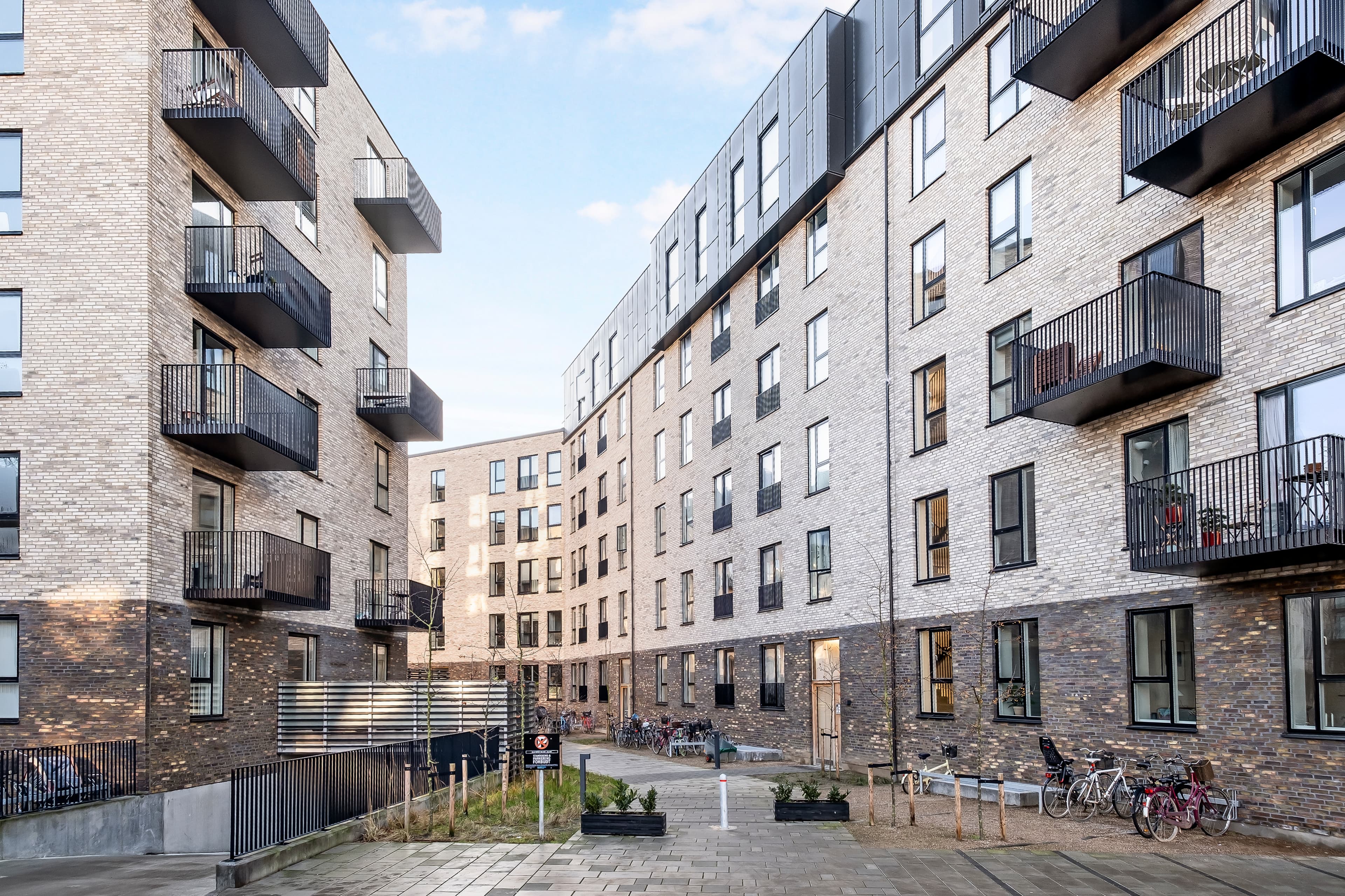The property seen from the outside between two of the buildings, with an access road leading into the courtyard at the property Øresundpark on Amager.