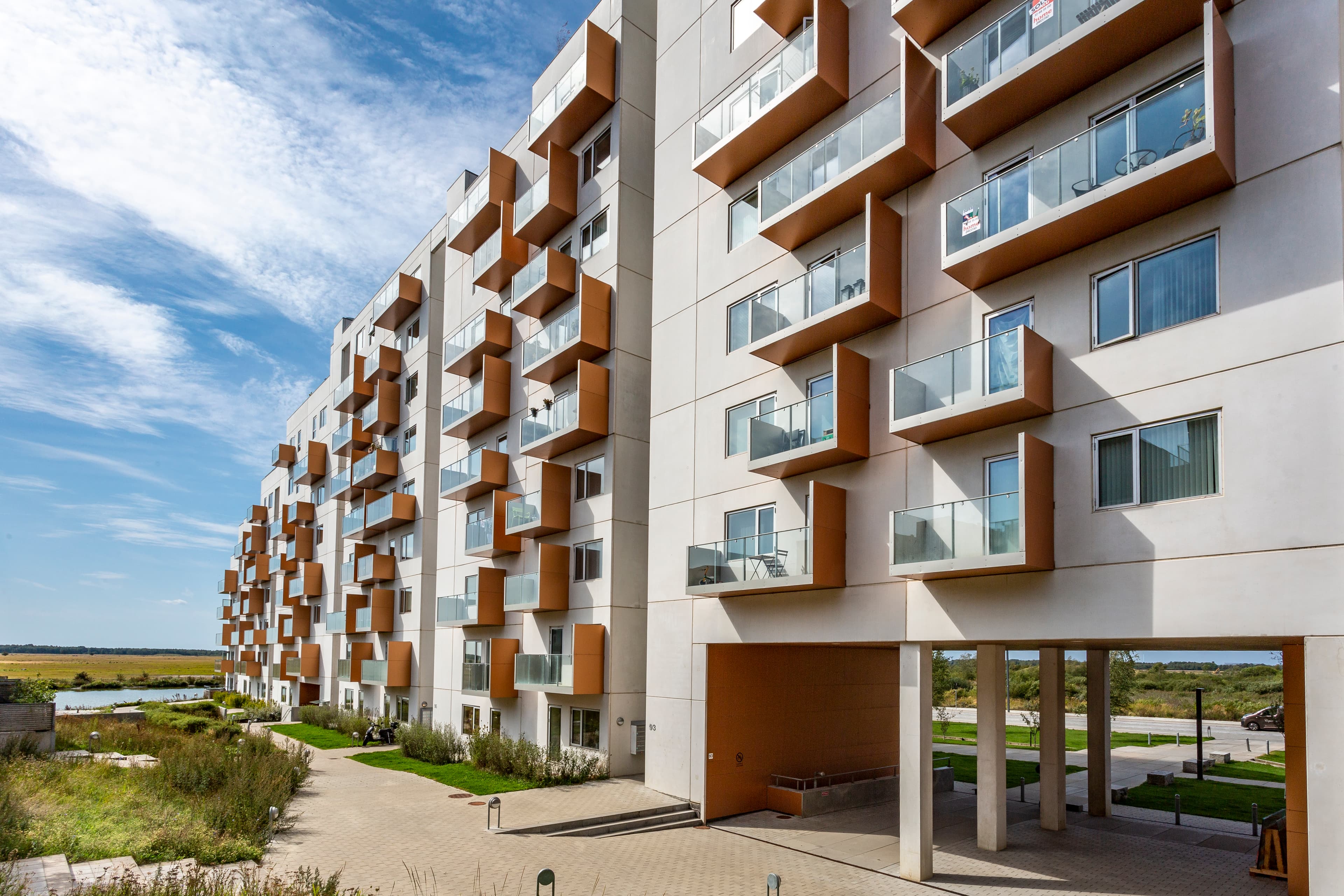 White façade with terracotta-coloured glass balconies at the property Hesteskoen in Ørestaden.
