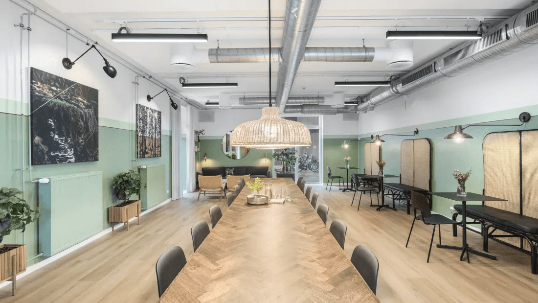 Fælleslokale med langbord, lamper og mange siddepladser i ejendommen Green Hills i Solrød