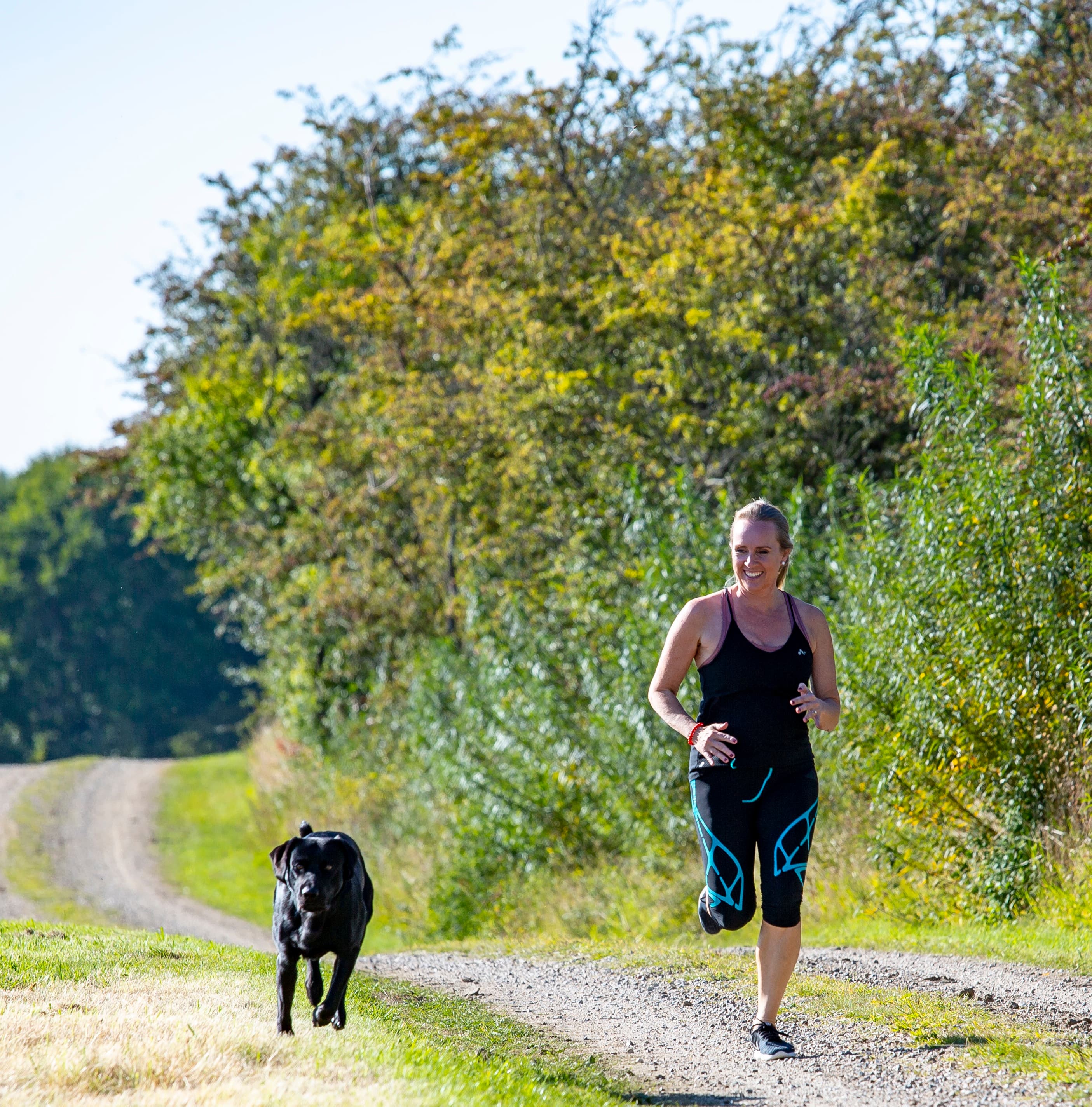 Kvinde løber med hund i skoven