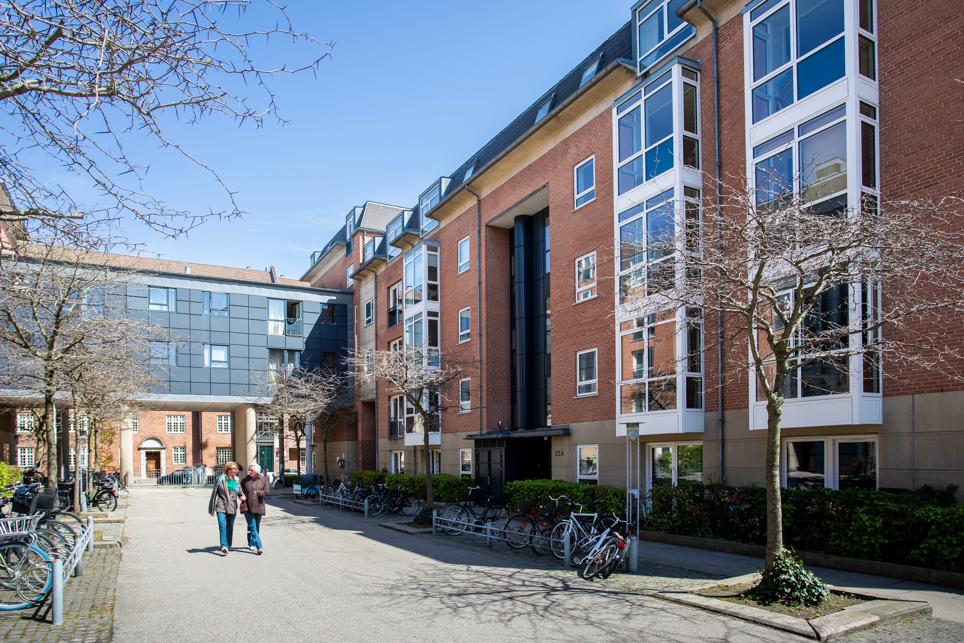 Eksteriørfoto af Østerfælled Torvs facade set inde fra gårdmiljøet med fælles udearealer i forgrunden.