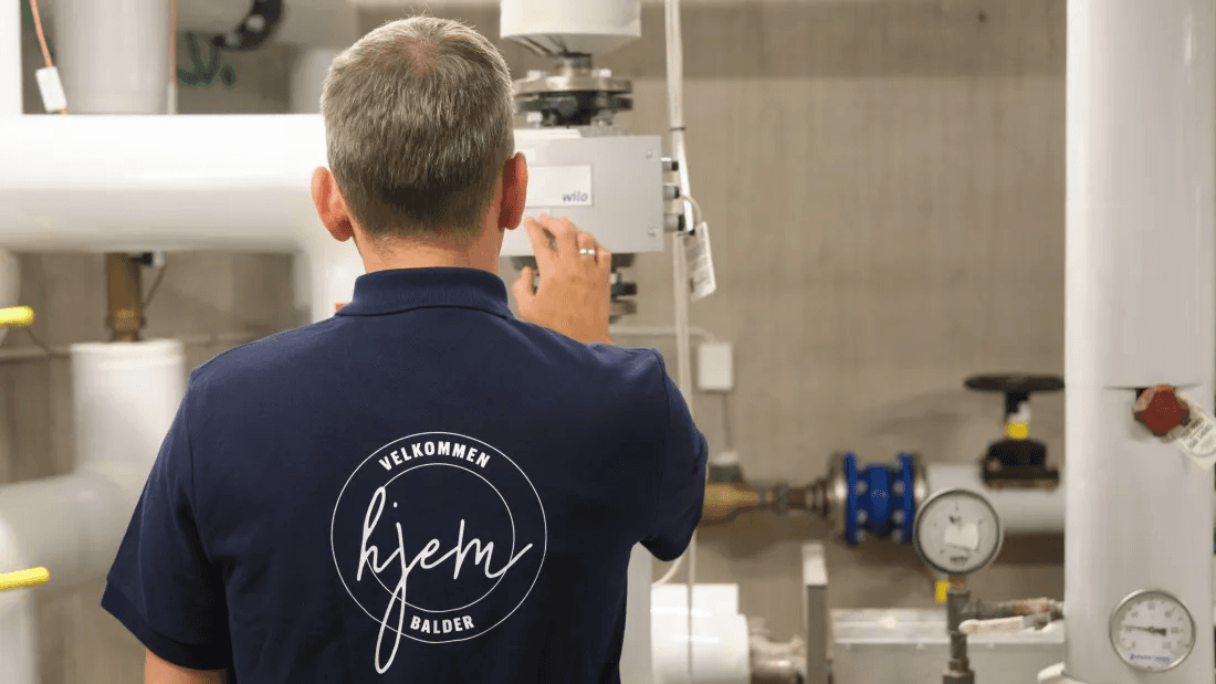 Drifttekniker fra Balder Danmark står ved varmepumpe